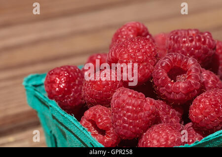 Organic red raspberries in a green basket fresh from the farmers market on a picnic table Stock Photo