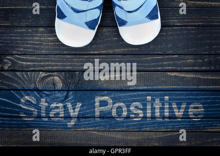 Stay Positive message and kid shoes on wooden floor Stock Photo