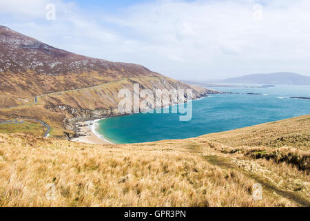 Gorgeous sunny day looking down at a secluded beach along a rugged coastline. Aqua-blue waters brush up against a sandy beach. Stock Photo