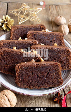 Chocolate sliced cake with nuts and spices for Christmas over rustic wooden background Stock Photo