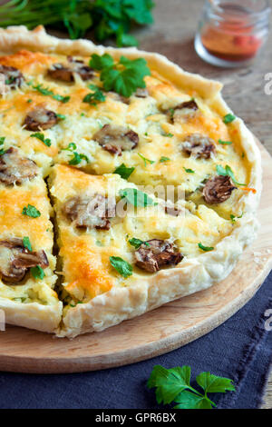 Homemade french quiche pie with mushrooms (champignons) and cheese over rustic wooden background close up Stock Photo