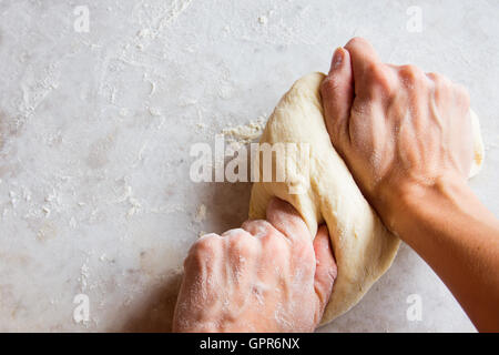Hands kneading dough on white table Stock Photo