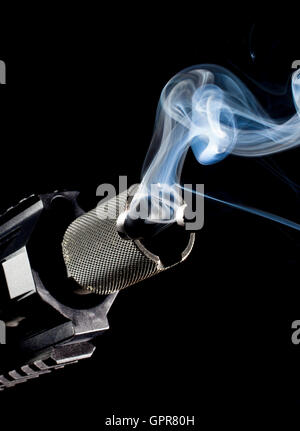 Smoke coming from the barrel of a weapon on a black background Stock Photo