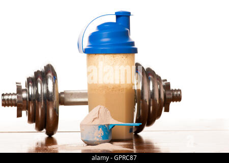 Whey protein powder in scoop, dumbbell, meter tape and plastic shaker on wooden background. Stock Photo