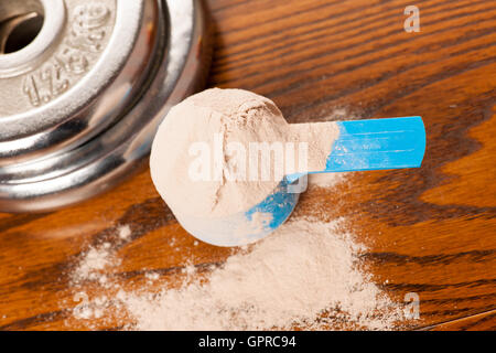 https://l450v.alamy.com/450v/gprc94/whey-protein-powder-in-measuring-scoop-and-dumbbell-on-wooden-background-gprc94.jpg