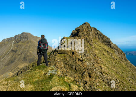 Walker on the summit ridge of Trollabhal in the Rum Cuillin hills, Isle of Rum, Scotland, UK.  Askival to the left. Stock Photo