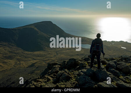 A walker on the summit ridge of Trollabhal in the Rum Cuillin hills looking over to Ruinsival, Isle of Rum, Scotland, UK. Stock Photo