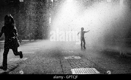 Two kids playing at the fountain. Stock Photo