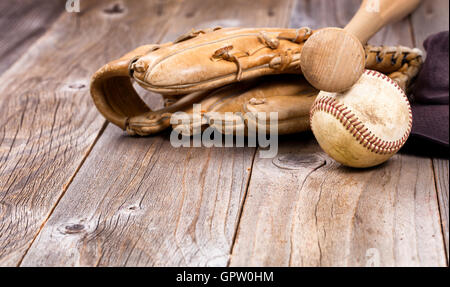 Old baseball equipment on rustic wooden boards. Selective focus on bat handle and ball. Stock Photo