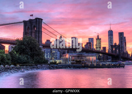 A colorful twilight view of the Brooklyn Bridge and the Manhattan skyline see from Empire Fulton Ferry Park in Brooklyn, NY Stock Photo