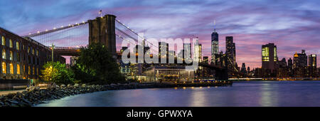 A colorful twilight view of the Brooklyn Bridge and the Manhattan skyline see from Empire Fulton Ferry Park in Brooklyn, NY