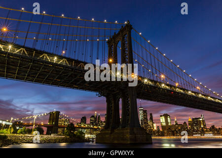 A colorful twilight view of the Manhattan and Brooklyn Bridges, and the Manhattan skyline see from John Street Park, Brookyn, NY Stock Photo