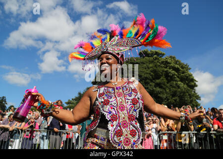 A woman dressed in a brightly coloured feathered headdress dances at the Leeds West Indian Carnival in Leeds, West Yorkshire. Stock Photo