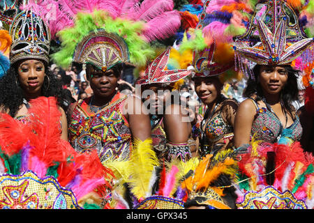 Women dressed in a brightly coloured feathered headdresses dance at the Leeds West Indian Carnival in Leeds, West Yorkshire. Stock Photo