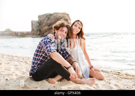 Portrait of cheerful young couple sitting on the beach Stock Photo