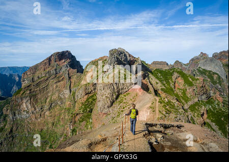 Woman hiker on the dangerous path between the rocky cliffs of Pico Arieiro. Stock Photo