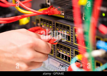 IT consultant connects a network cable into switch in datacenter Stock Photo