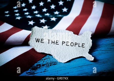 the text we the people, the first words of the United States Constitution, written in a piece of paper in the shape of the Unite Stock Photo