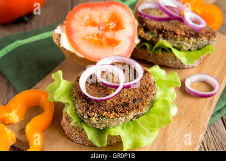 Vegetarian lentil burger with vegetables on wooden cutting board Stock Photo