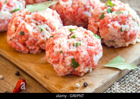 Cooking meatballs with vegetables, rice and spices on wooden cutting board close up Stock Photo