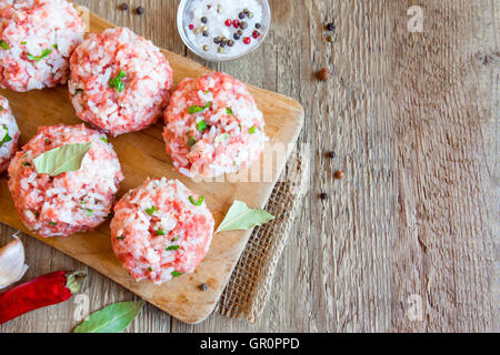 Cooking meatballs with vegetables, rice and spices on wooden cutting board with copy space Stock Photo