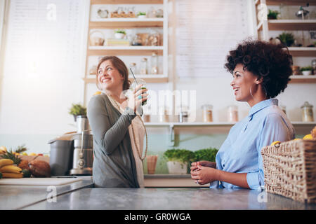 Two young female juice bar employees standing behind counter. Young women working at fruit juice bar. Stock Photo