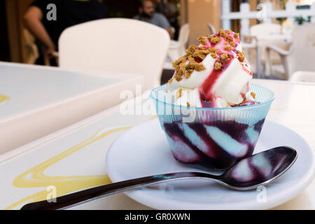 frozen yogurt with black cherry topping and amaretto grains in an outdoor cafe Stock Photo