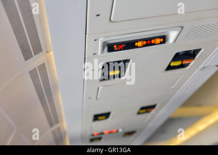 No Smoking and Fasten Seat Belt sign inside an passenger airplane cabin closeup Stock Photo