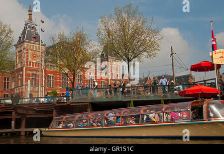 Canal Tour Boat passes in front of Centraal Station, Amsterdam, Holland Stock Photo