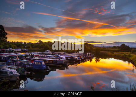 Rufford, Lancashire, UK. 6th September, 2016. UK Weather. Extraordinary temperatures of 19C at dawn as the morning sun and red clouds are reflected in the calm waters of the canal basin. Higher temperatures are expected as southern winds drag warm continental air inland as aircraft condensation trails form an arc colourfully highlighting the route to Manchester. Credit:  MediaWorld Images/Alamy Live News Stock Photo