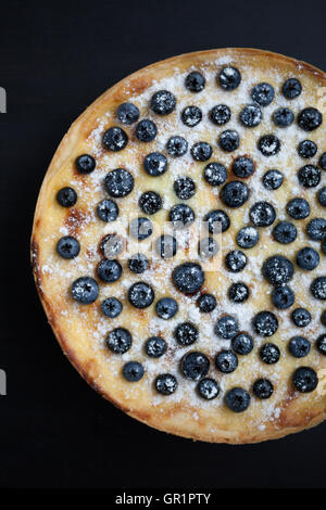 Overhead shot of fresh homemade blueberry pie with cream and sugar powder. Close up macro, vertical. Delicious pastry dessert Stock Photo