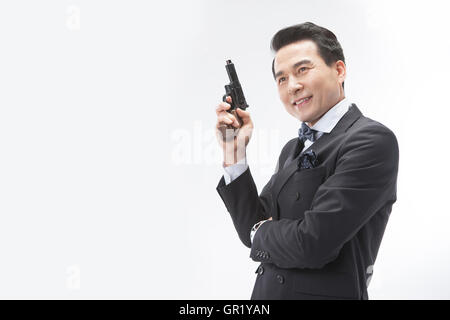 Portrait of smiling middle aged man in suit holding a gun Stock Photo