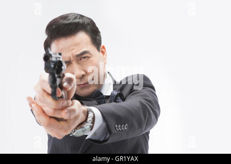 Portrait of middle aged man in suit holding a gun winking Stock Photo