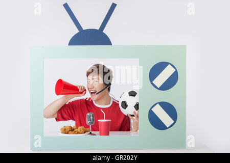 Portrait of young man holding megaphone and soccer ball on television Stock Photo