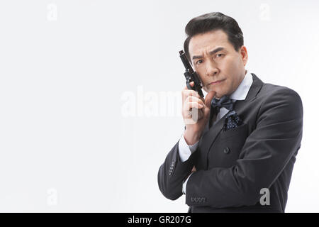 Portrait of middle aged man in suit posing with a gun frowning face Stock Photo