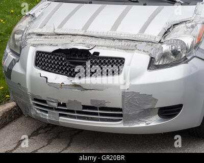 Tape-based Auto Repair. A silver car is patched with grey duct tape after an accident has caused some front-end damage. Stock Photo