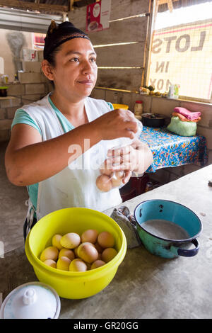 Selling Eggs by the Baggie. A fast food vendor packs up half a dozen brown eggs for a customer in her small cooking shack. Stock Photo