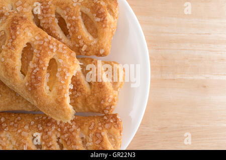 Top close view of a group of sugar coated apple fruit tarts on a plate with one bitten atop a wood table. Stock Photo