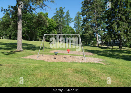 A toddler's swing set that is empty in a park setting. Stock Photo
