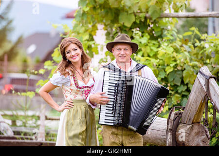 Couple in traditional bavarian clothes with accordion, green gar Stock Photo