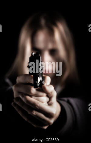 serious girl with gun aiming in dark Stock Photo