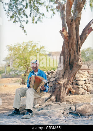 Grigorio Viaz nicknamed 'Code de Dona' ( Grandmothers's favorite) sits outside his home in Sao Francisco playing his accordion. Stock Photo