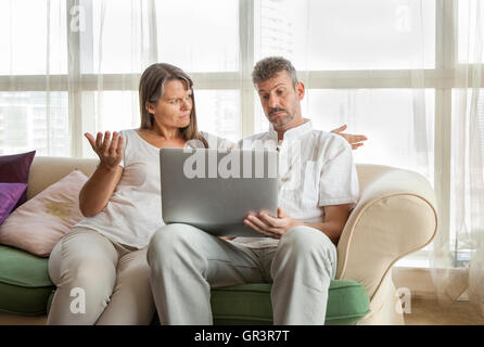 middle aged couple looking at a computer and having a disagreement Stock Photo