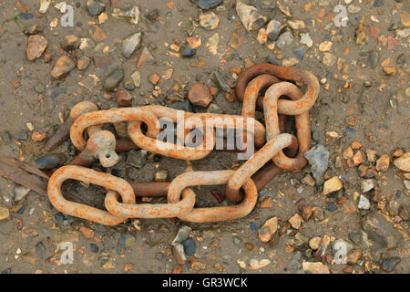 Rusty chain on shingle Stock Photo