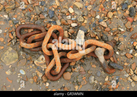 Rusty chain on shingle Stock Photo