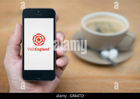 A man looks at his iPhone which displays the Visit England logo (Editorial use only). Stock Photo