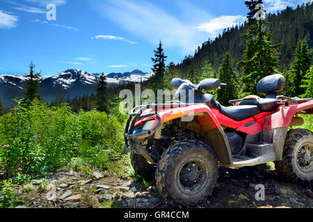 Red Black ATV (All Terrain Vehicle) Parked on Mountainous Forest Gravel Road near Sunny Whistler BC. HDR Nature Horizontal Photo Stock Photo