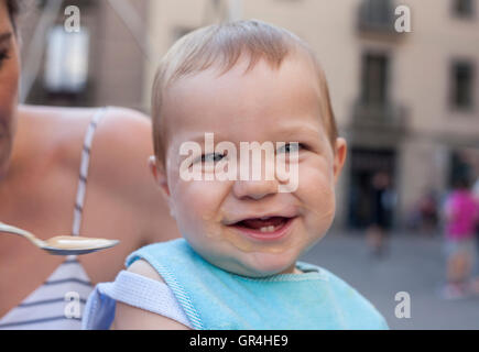 Mother feeding her happy baby boy with fruit mush outdoors Stock Photo