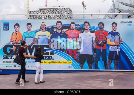 Couple watching a giant billboard promoting the Barclays ATP World Tour Finals 2016 which will be held in London 13-20 November Stock Photo