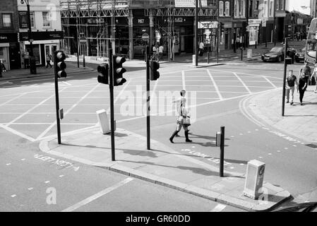 - 10 July 2016: Couple crossing the road at a pedestrian crossing with traffic lights in Shoreditch, East London. Stock Photo